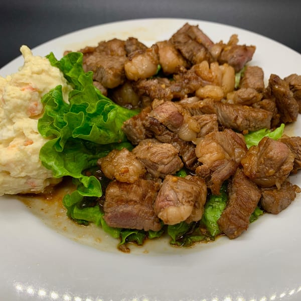 Edomasa Sushi Bar's beef dish with lettuce and a side of potato salad on a white plate.